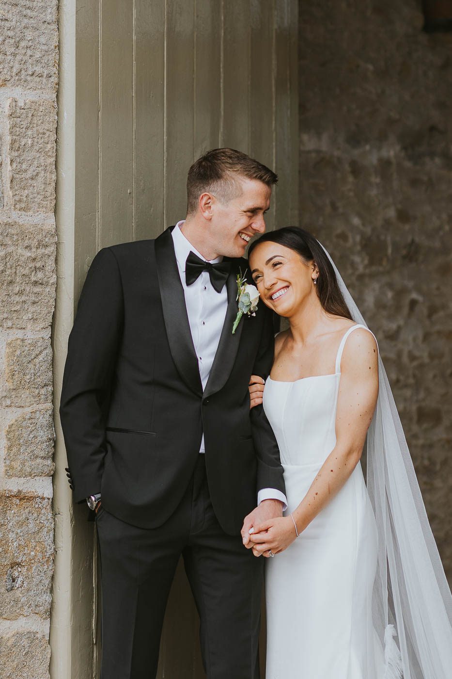tithe barn bolton abbey wedding photos | relaxed photo of bride and groom laughing at the tithe barn | elegant black tie wedding at yorkshire's best barn venue